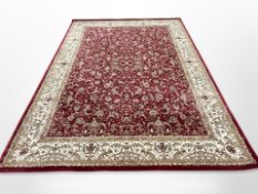 A machine-made carpet of Persian design on red ground, 336cm x 241cm.