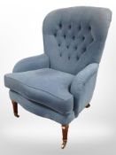 A Victorian style armchair in blue upholstery, raised on brass castors,