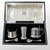 A three-piece silver condiment set, with spoons, in fitted case.