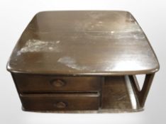 An Ercol dark elm Pandora's box coffee table on castors, 80cm wide x 40cm high.