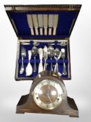 An Art Deco oak mantel clock and an oak canteen containing a part stainless steel cutlery set.