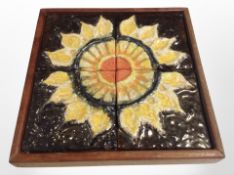 A 20th century Scandinavian teak framed ceramic plaque depicting a sun flower,