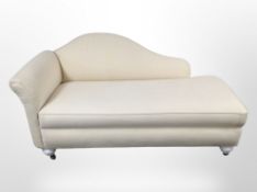 A reproduction chaise longue in beige fabric, raised on castors,