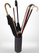 A pottery vase containing walking sticks, parasol with gold-plated ferrule.