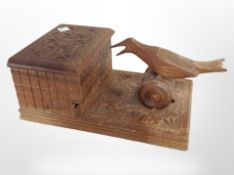 A carved cigarette dispenser surmounted by a bird, length 23cm.