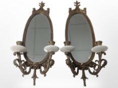 A pair of contemporary oval brass and ceramic twin-sconce wall mirrors, length 58cm.