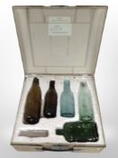 A vintage case containing a group of antique glass bottles bearing various advertising.
