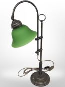 A reproduction brass rise and fall desk lamp with green glass shade.