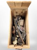 A pine crate with rope handles containing assorted tools and hardware.