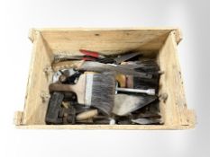 A pine crate containing various tools, brushes, hand saws, etc.
