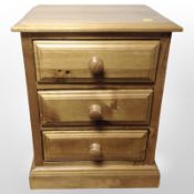 A contemporary pine three-drawer bedside chest,