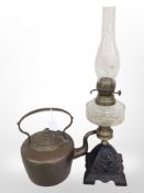 A Victorian copper kettle and an oil lamp with cast-iron base and clear glass reservoir,