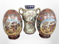 A pair of 20th-century Japanese earthenware egg ornaments on turned wooden stand,