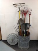 A galvanised bin containing assorted garden tools.