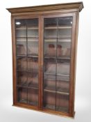 A late-Victorian mahogany and pine glazed double-door bookcase, 122cm wide x 32cm deep x 173cm high.