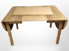 A Danish blonde oak extending drop-leaf dining table with two leaves,