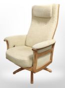 An Ercol elm reclining swivel armchair in beige upholstery.