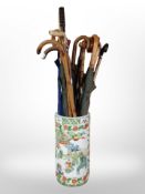 An oriental export porcelain cylindrical stick stand, height 43cm, containing various umbrellas.