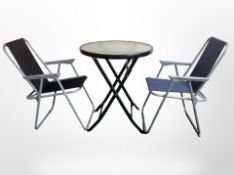 A contemporary glass-topped patio table, together with a folding chair, diameter 60cm.
