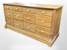 A contemporary pine 12-drawer sideboard, 166cm wide x 58cm deep x 82cm hIgh.