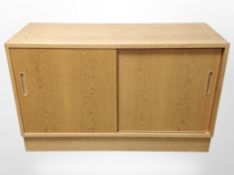A 20th-century Danish oak veneered sliding-door low cabinet designed by Poul Hundevad,