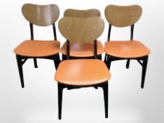 A set of four ebonised and laminated ply dining chairs with orange leather seats.