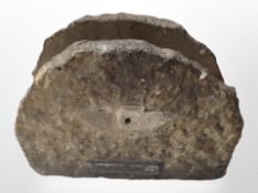 A weathered stone ornament with plaque inscribed 'This stone came from the Houses of Parliament',