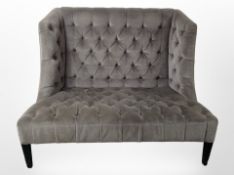 A contemporary two-seater wingback settee in buttoned grey upholstery,