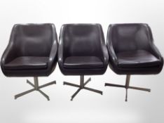 A set of three stitched brown leather swivel armchairs on metal bases, width 57cm.
