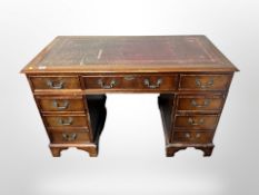 A reproduction mahogany desk fitted nine drawers and tooled-leather inset panel,