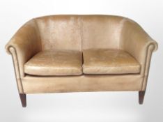 A 20th-century faded tan leather two-seater settee, 142cm wide x 84cm deep x 86cm high.