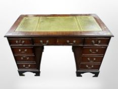 A reproduction mahogany nine-drawer desk with tooled-leather inset panel,