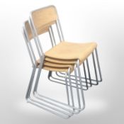 A set of four bent and laminated wood metal stacking chairs.