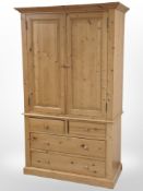 A contemporary pine double-door wardrobe fitted four drawers beneath,
