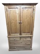 A contemporary pine double-door wardrobe fitted four drawers beneath,