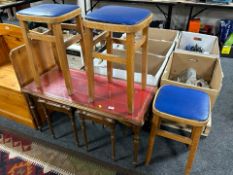A nest of three tables with red tooled-leather inset tops, together with three vinyl-topped stools.