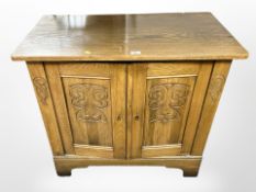 A 20th-century carved-oak double-door cabinet, 89cm wide x 45cm deep x 83cm high.