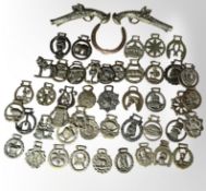 A collection of Victorian and later horse brasses, pair of brass pistols, horse shoe.