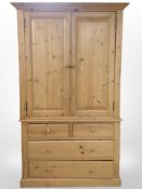 A contemporary pine double-door wardrobe fitted four drawers beneath,