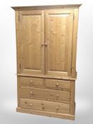 A contemporary pine double-door wardrobe fitted four drawers beneath,