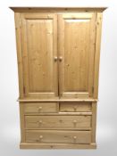 A contemporary pine double-door wardrobe fitted four drawers beneath,