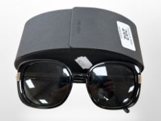 A pair of Prada sun glasses in retail case