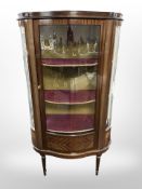 A 20th-century glazed mahogany serpentine-front display cabinet, 80cm wide x 37cm deep x 142cm high.
