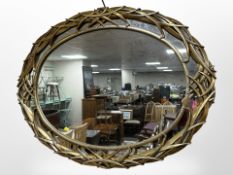 An ornate reproduction oval gilt wall mirror, 99cm x 75cm.