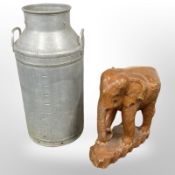 An aluminium milk churn and a carved figure of an elephant.