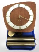 A teak and brass wall clock with pendulum and weights.