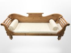 A pine three seater settee in classical upholstery and two bolster cushions,