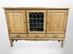 A Danish blonde oak sideboard with stained and leaded glass central door,