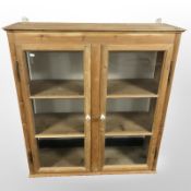 An early 20th century glazed pine double door wall cabinet,