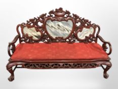 A reproduction Chinese carved hardwood three seater settee with marble-inset backrest,